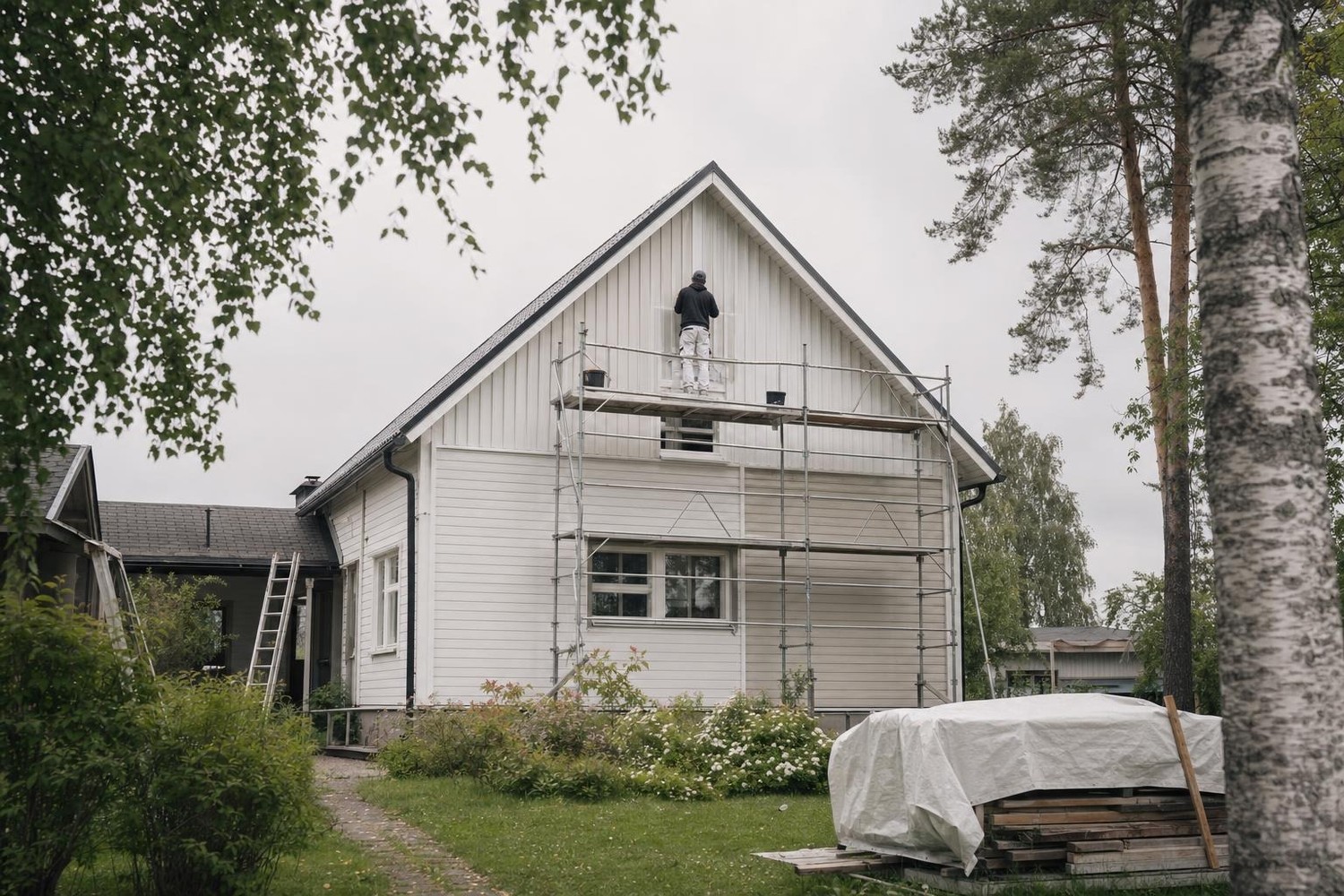 Maalari telineillä omakotitalon päätyseinällä